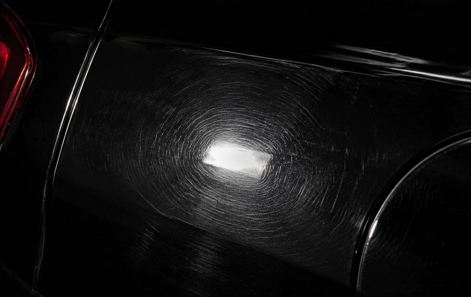 Swirl marks on dark car paint under a hard raking inspection light before paint correction in Bolingbrook, IL